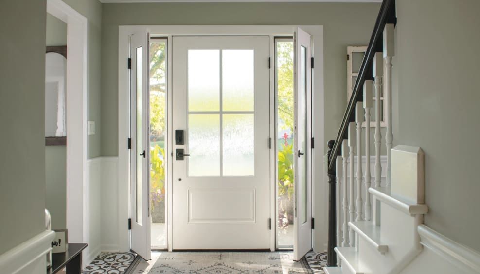 A white door with two windows and a black stair railing.