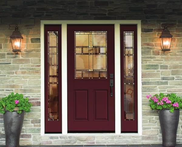 A red door with two windows and flower pots on the side.